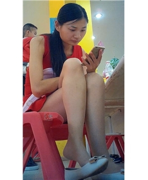 边玩手机边挑些等孩子玩蹦蹦床的红衣少f