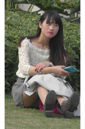 草地上玩手机的美女